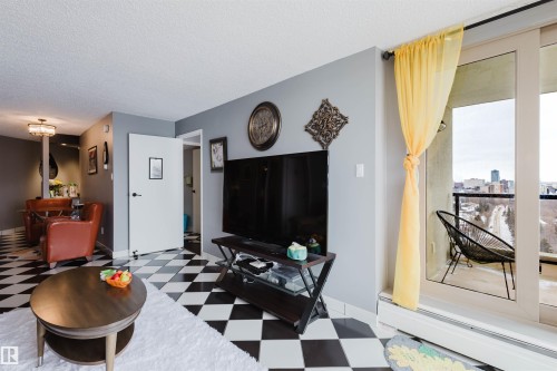 Living room with light flooring, a textured ceiling, and a baseboard heating unit - 1803 10149 Saskatchewan Drive, Edmonton, AB - Indoor