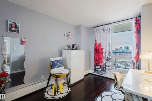 Dining room featuring dark wood-style floors, a textured ceiling, a skyline view, and a baseboard heating unit - 1803 10149 Saskatchewan Drive, Edmonton, AB - Indoor