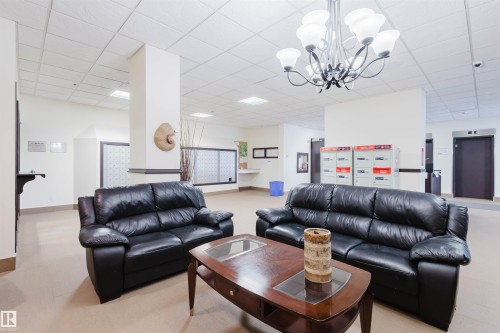 Living room with a paneled ceiling, elevator, and a chandelier - 1803 10149 Saskatchewan Drive, Edmonton, AB - Indoor Photo Showing Living Room
