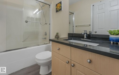Bathroom featuring vanity, combined bath / shower with glass door, and wood finished floors - 2348 28B Avenue, Edmonton, AB - Indoor Photo Showing Bathroom