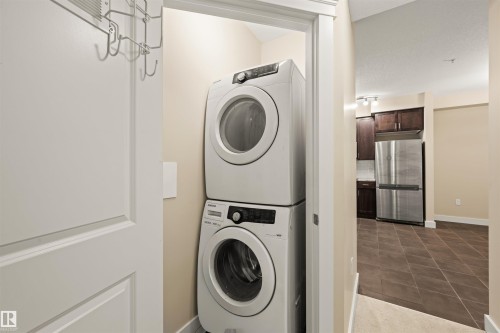 Laundry area featuring stacked washer and clothes dryer and dark tile patterned flooring - 29 11518 76 Avenue, Edmonton, AB - Indoor Photo Showing Laundry Room