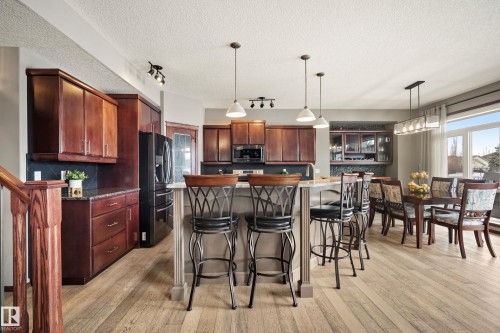 Kitchen featuring a breakfast bar area, stainless steel appliances, light wood-style flooring, a kitchen island, and decorative backsplash - 19 Rosemount Boulevard, Beaumont, AB - Indoor