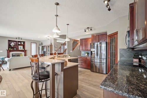 Kitchen featuring stainless steel appliances, rail lighting, tasteful backsplash, a breakfast bar, and open floor plan - 19 Rosemount Boulevard, Beaumont, AB - Indoor Photo Showing Kitchen With Upgraded Kitchen