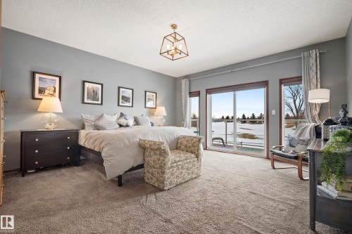 Bedroom featuring access to exterior, carpet, a textured ceiling, and a water view - 19 Rosemount Boulevard, Beaumont, AB - Indoor Photo Showing Bedroom