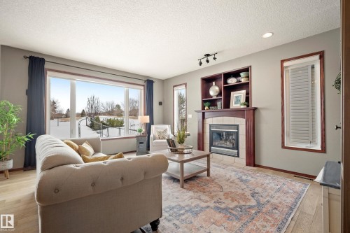 Living room with light wood-style flooring, a textured ceiling, a tile fireplace, and rail lighting - 19 Rosemount Boulevard, Beaumont, AB - Indoor Photo Showing Living Room With Fireplace