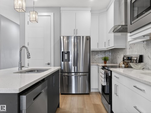 Kitchen with stainless steel appliances, light stone countertops, light wood-style flooring, decorative light fixtures, and decorative backsplash - 9358 Pear Link Link, Edmonton, AB - Indoor Photo Showing Kitchen With Upgraded Kitchen