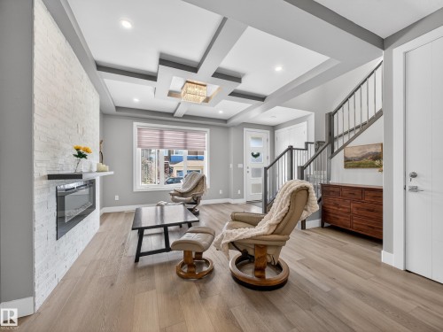 Living area with coffered ceiling, a stone fireplace, and light wood-type flooring - 9358 Pear Link Link, Edmonton, AB - Indoor
