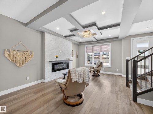 Sitting room featuring coffered ceiling, a fireplace, light wood-type flooring, and recessed lighting - 9358 Pear Link Link, Edmonton, AB - Indoor With Fireplace