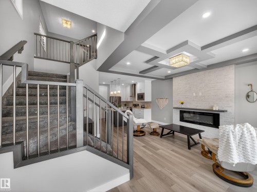 Stairway featuring a fireplace, wood finished floors, coffered ceiling, and hanging lights - 9358 Pear Link Link, Edmonton, AB - Indoor Photo Showing Other Room