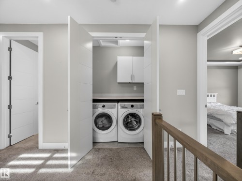 Laundry room featuring light carpet, washing machine and clothes dryer, and cabinet space - 9358 Pear Link Link, Edmonton, AB - Indoor Photo Showing Laundry Room