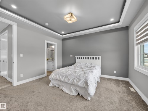 Bedroom featuring a tray ceiling, light colored carpet, ensuite bathroom, and recessed lighting - 9358 Pear Link Link, Edmonton, AB - Indoor Photo Showing Bedroom