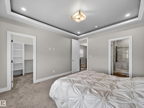 Carpeted bedroom featuring a tray ceiling, a spacious closet, ensuite bath, and recessed lighting - 9358 Pear Link Link, Edmonton, AB - Indoor Photo Showing Bedroom