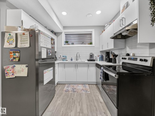 Kitchen featuring stainless steel appliances, white cabinetry, light wood-style flooring, tasteful backsplash, and open shelves - 9358 Pear Link Link, Edmonton, AB - Indoor Photo Showing Kitchen