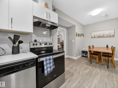 Kitchen with stainless steel appliances, light wood-type flooring, white cabinets, decorative backsplash, and light stone counters - 9358 Pear Link Link, Edmonton, AB - Indoor Photo Showing Kitchen