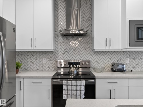 Kitchen with stainless steel appliances, white cabinetry, and light stone countertops - 9358 Pear Link Link, Edmonton, AB - Indoor Photo Showing Kitchen With Upgraded Kitchen