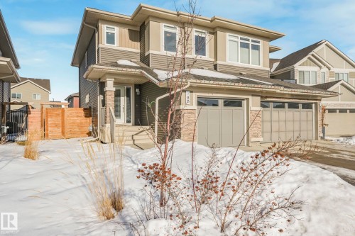View of front of house featuring concrete driveway, stone siding, an attached garage, and a gate - 97 James Cres, St. Albert, AB - Outdoor