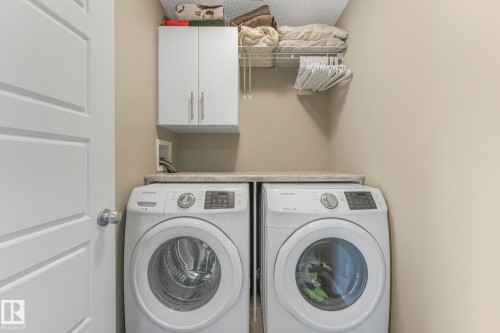 Laundry area with washing machine and dryer, cabinet space, and a textured ceiling - 97 James Cres, St. Albert, AB - Indoor Photo Showing Laundry Room