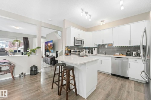 Kitchen featuring tasteful backsplash, a breakfast bar, stainless steel appliances, and white cabinetry - 97 James Cres, St. Albert, AB - Indoor Photo Showing Kitchen With Upgraded Kitchen