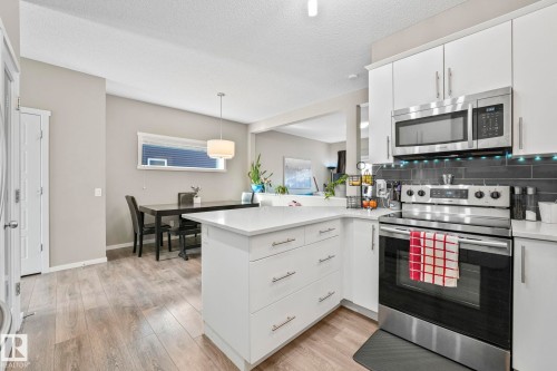 Kitchen featuring stainless steel appliances, a peninsula, white cabinetry, backsplash, and a textured ceiling - 97 James Cres, St. Albert, AB - Indoor Photo Showing Kitchen