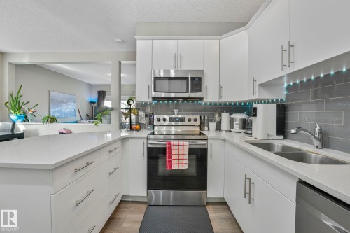 Kitchen featuring stainless steel appliances, light stone counters, tasteful backsplash, white cabinetry, and a textured ceiling - 97 James Cres, St. Albert, AB - Indoor Photo Showing Kitchen With Double Sink