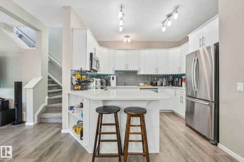 Kitchen with stainless steel appliances, a breakfast bar area, a peninsula, white cabinets, and a textured ceiling - 97 James Cres, St. Albert, AB - Indoor Photo Showing Kitchen With Upgraded Kitchen