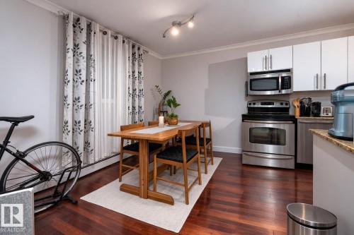 Dining room with dark wood-style floors, crown molding, and baseboard heating - 7 10525 83 Avenue, Edmonton, AB - Indoor
