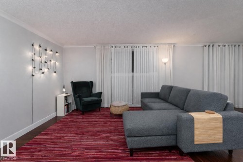 Living room featuring a textured ceiling, wood finished floors, and crown molding - 7 10525 83 Avenue, Edmonton, AB - Indoor Photo Showing Living Room