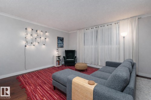 Living area with a textured ceiling, wood finished floors, and ornamental molding - 7 10525 83 Avenue, Edmonton, AB - Indoor Photo Showing Living Room