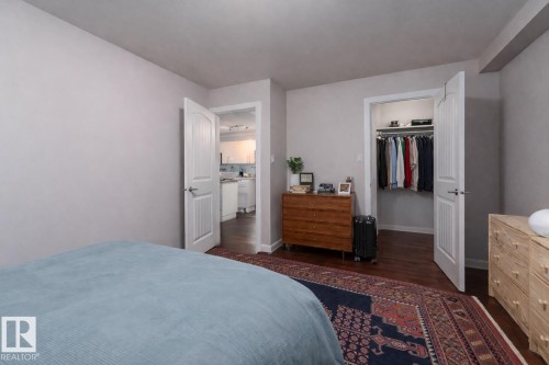 Bedroom featuring a walk in closet and dark wood-style flooring - 7 10525 83 Avenue, Edmonton, AB - Indoor Photo Showing Bedroom