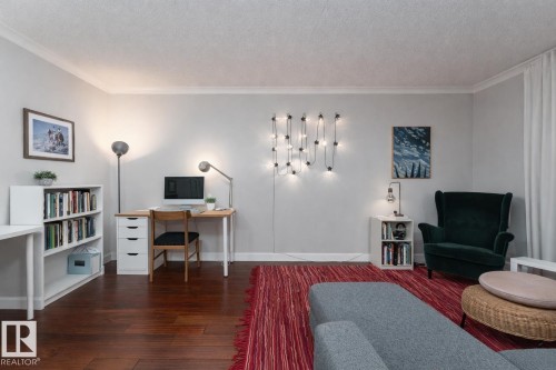 Office space featuring dark wood-style flooring, crown molding, and a textured ceiling - 7 10525 83 Avenue, Edmonton, AB - Indoor Photo Showing Other Room