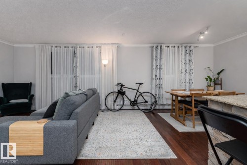 Living area featuring crown molding and dark wood-style flooring - 7 10525 83 Avenue, Edmonton, AB - Indoor