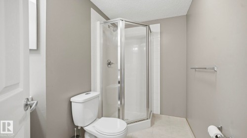 Bathroom with a shower stall, a textured ceiling, and light tile patterned floors - 401 636 Mcallister Loop, Edmonton, AB - Indoor Photo Showing Bathroom