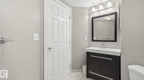 Half bath with vanity, light tile patterned flooring, and a textured ceiling - 401 636 Mcallister Loop, Edmonton, AB - Indoor Photo Showing Bathroom