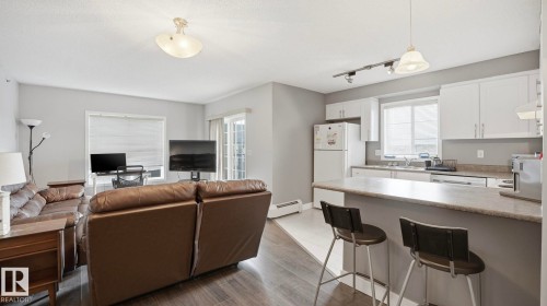 Living area with baseboard heating, light wood-style flooring, and rail lighting - 401 636 Mcallister Loop, Edmonton, AB - Indoor Photo Showing Kitchen