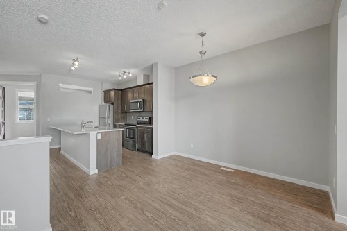 Kitchen featuring stainless steel appliances, pendant lighting, an island with sink, light wood-style flooring, and a textured ceiling - 2577 Coughlan Road, Edmonton, AB - Indoor Photo Showing Kitchen