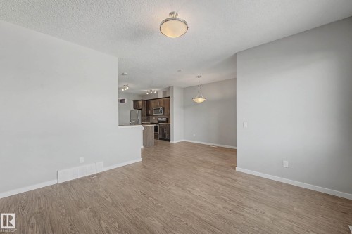 Unfurnished living room with light wood-style floors and a textured ceiling - 2577 Coughlan Road, Edmonton, AB - Indoor Photo Showing Other Room