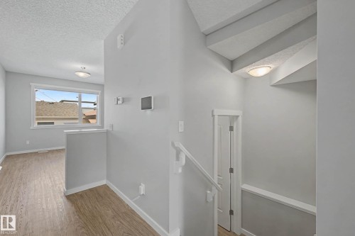 Hallway featuring an upstairs landing, a textured ceiling, and light wood finished floors - 2577 Coughlan Road, Edmonton, AB - Indoor Photo Showing Other Room