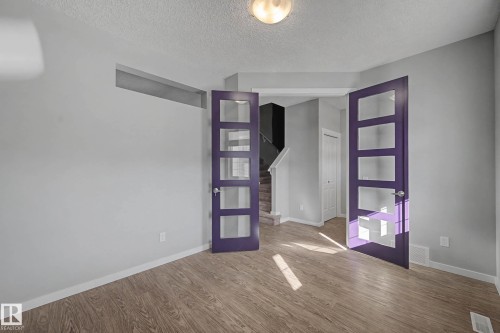 Empty room with wood finished floors, a textured ceiling, and french doors - 2577 Coughlan Road, Edmonton, AB - Indoor Photo Showing Other Room