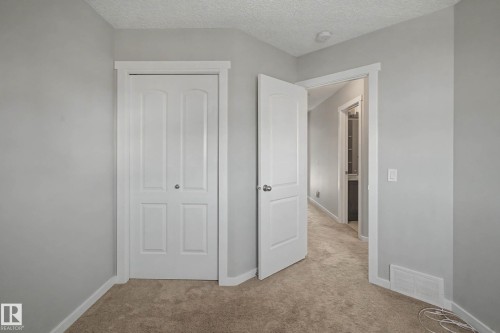 Unfurnished bedroom with light carpet, a textured ceiling, and a closet - 2577 Coughlan Road, Edmonton, AB - Indoor