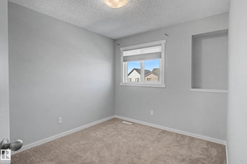 Carpeted spare room featuring a textured ceiling and baseboards - 2577 Coughlan Road, Edmonton, AB - Indoor Photo Showing Other Room
