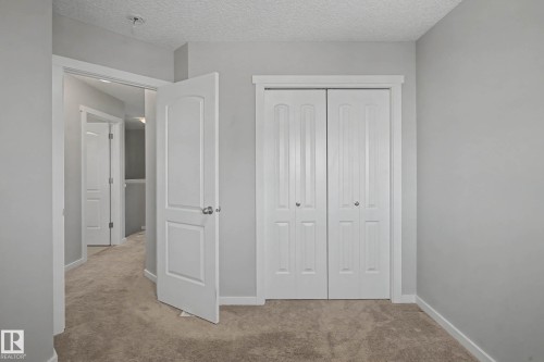Unfurnished bedroom with light colored carpet, a closet, and a textured ceiling - 2577 Coughlan Road, Edmonton, AB - Indoor