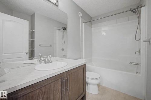 Full bath featuring vanity, a textured ceiling, shower / washtub combination, and light tile patterned flooring - 2577 Coughlan Road, Edmonton, AB - Indoor Photo Showing Bathroom