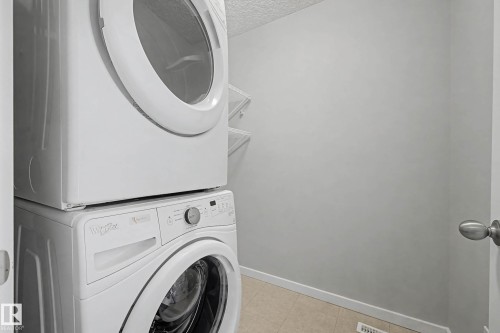 Laundry area featuring stacked washer / dryer and a textured ceiling - 2577 Coughlan Road, Edmonton, AB - Indoor Photo Showing Laundry Room