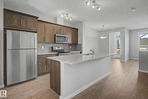 Kitchen featuring stainless steel appliances, light wood-style flooring, backsplash, a center island with sink, and pendant lighting - 2577 Coughlan Road, Edmonton, AB - Indoor Photo Showing Kitchen With Stainless Steel Kitchen With Upgraded Kitchen