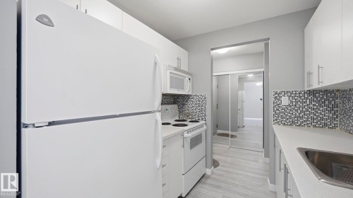 Kitchen with white appliances, white cabinets, light countertops, and tasteful backsplash - 103 1624 48 Street, Edmonton, AB - Indoor Photo Showing Kitchen