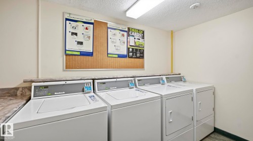 Community laundry featuring a textured ceiling and independent washer and dryer - 103 1624 48 Street, Edmonton, AB - Indoor Photo Showing Laundry Room