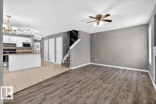 Kitchen with open floor plan, white cabinets, light wood-style floors, pendant lighting, and appliances with stainless steel finishes - 150 Acacia Circle, Leduc, AB - Indoor Photo Showing Kitchen