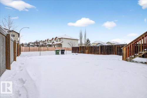 Snowy yard with a residential view, a fenced backyard, and stairs - 150 Acacia Circle, Leduc, AB - Outdoor