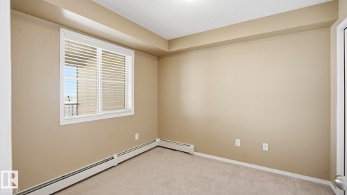 Unfurnished room with a baseboard heating unit, a textured ceiling, and light colored carpet - 319 274 Mcconachie Drive, Edmonton, AB - Indoor Photo Showing Other Room