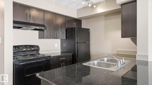 Kitchen with black appliances and dark stone counters - 319 274 Mcconachie Drive, Edmonton, AB - Indoor Photo Showing Kitchen With Double Sink